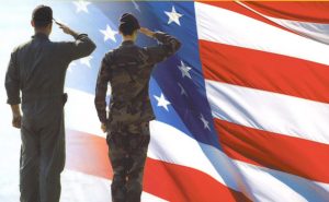 Military service members saluting the American Flag